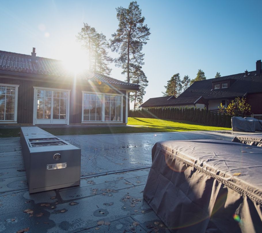 Basseng med overdekke ved brunt hus